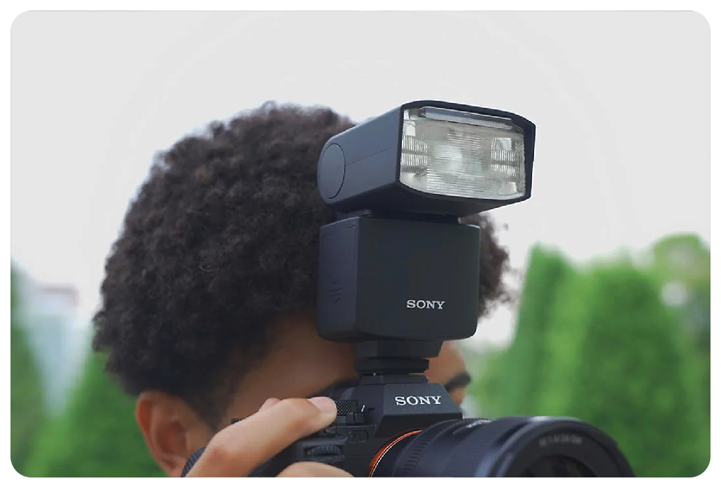 close up of photographer holding Sony A7 IV Camera and sony flash gun to their eye